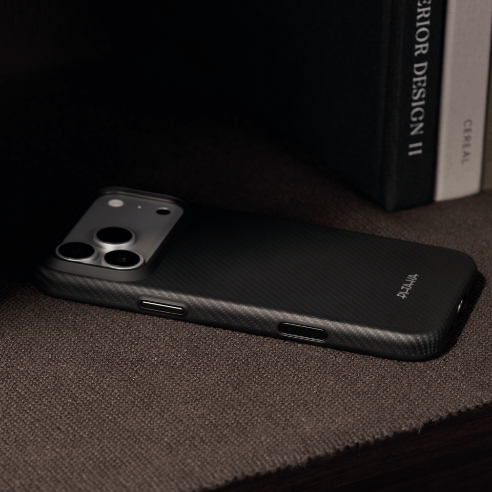 iPhone 18 Pro Max Karbon Kılıf Summa 600D Black Gray - kitapların önünde yatay duran görünüm
